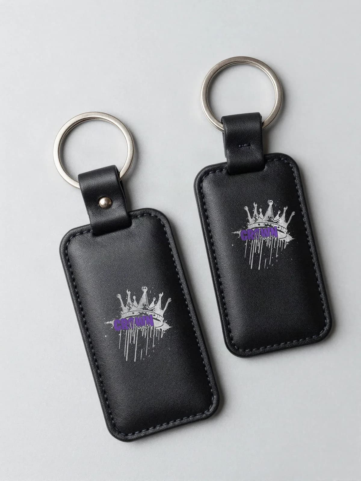 Zwei schwarze Leder-Anhänger mit Crown-Visuals-Logo